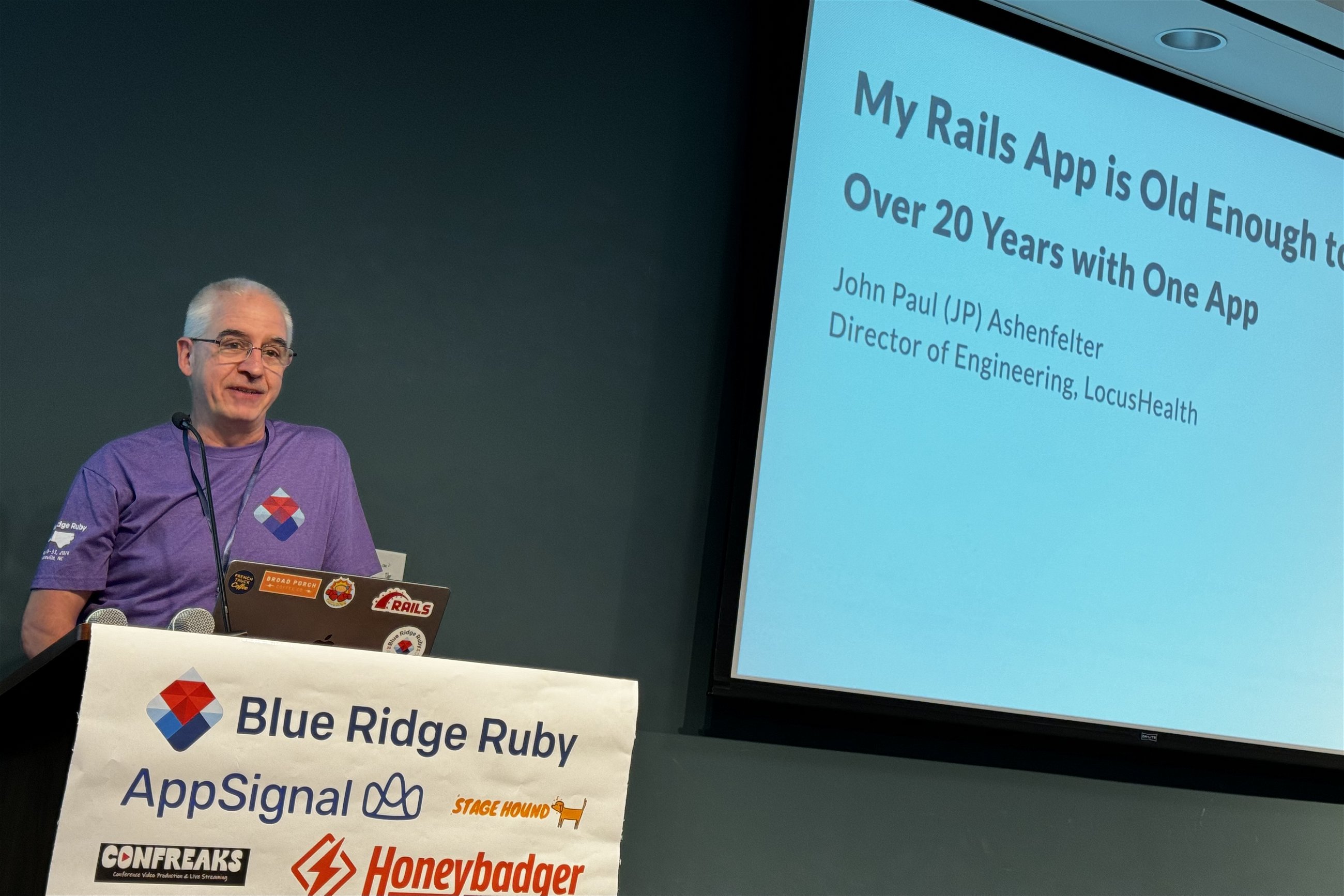 John Paul Ashenfelter at Blue Ridge Ruby conference discussing his long-term experience with a Rails application, titled "My Rails App is Old Enough to Drink: Over 20 Years with One App."
